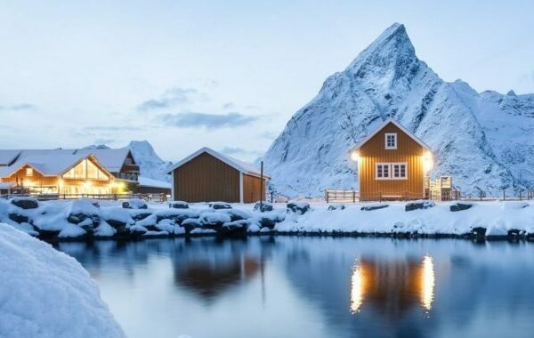 Rorbuer ved sjøen under snødekte fjell